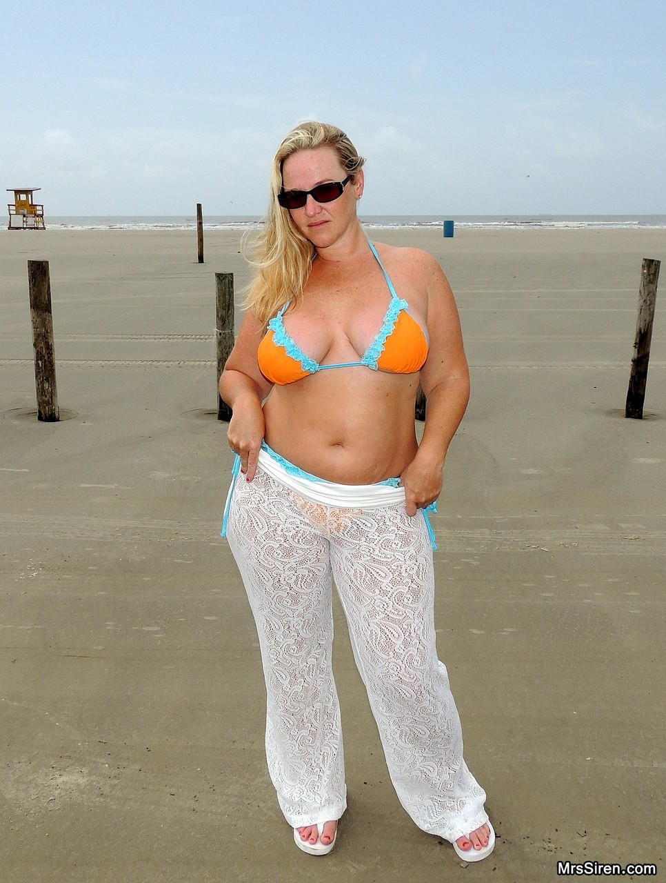 Short MILF Dee Siren strips on the beach & exposes her monster curves
