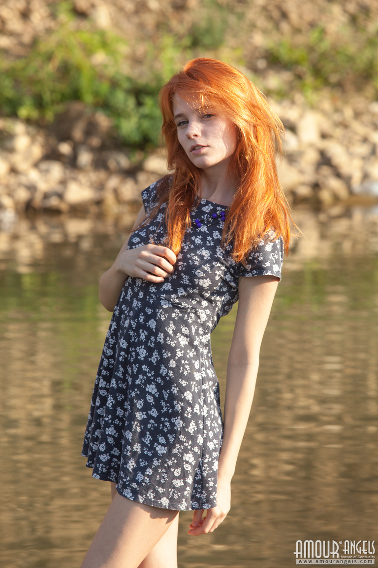 Sexy redheaded teen poses her thin body in the nude by a stream