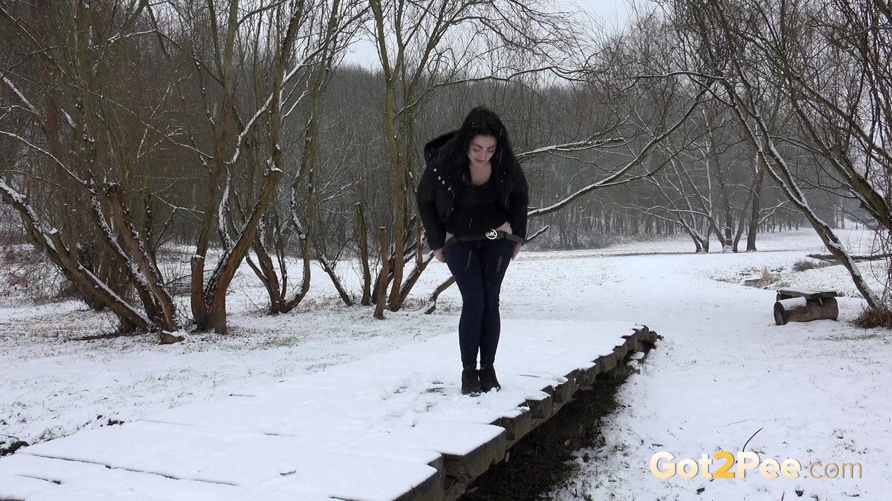 Dark haired girl pees on a bridge in the snow