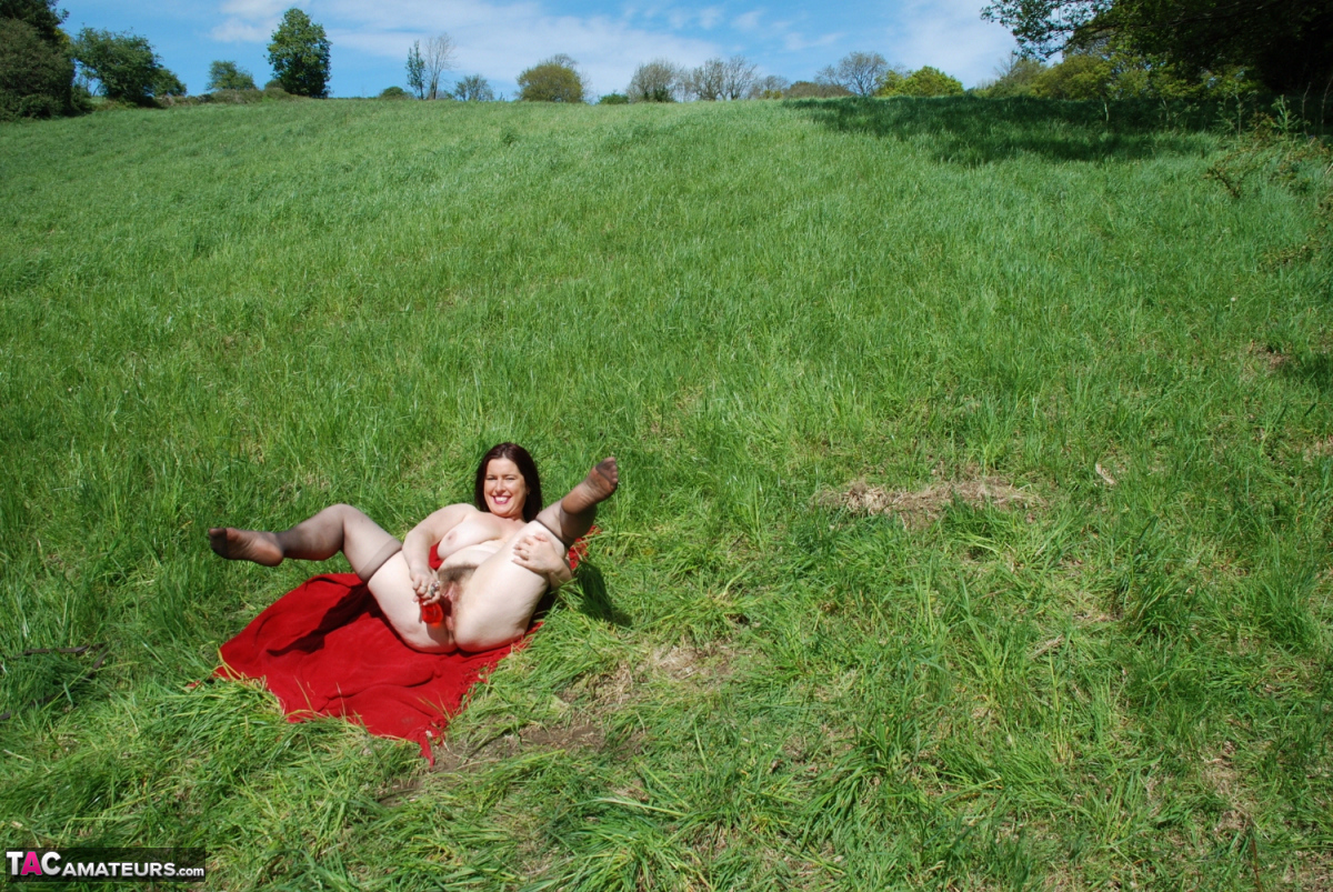 British amateur Juicey Janey dildos her bush on a red blanket in a field