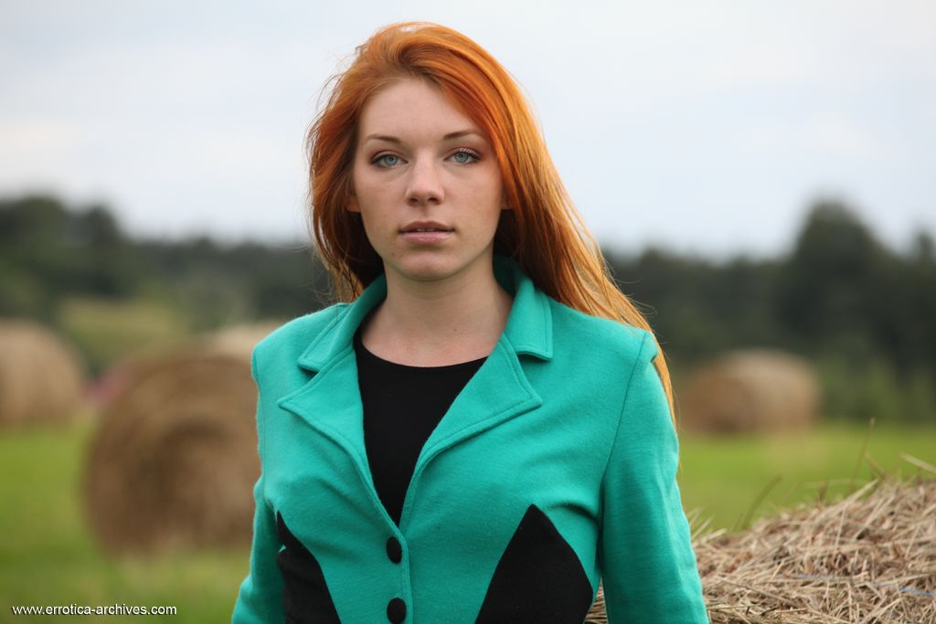 Redheaded teen Amber A gets totally naked against a round bale in a field