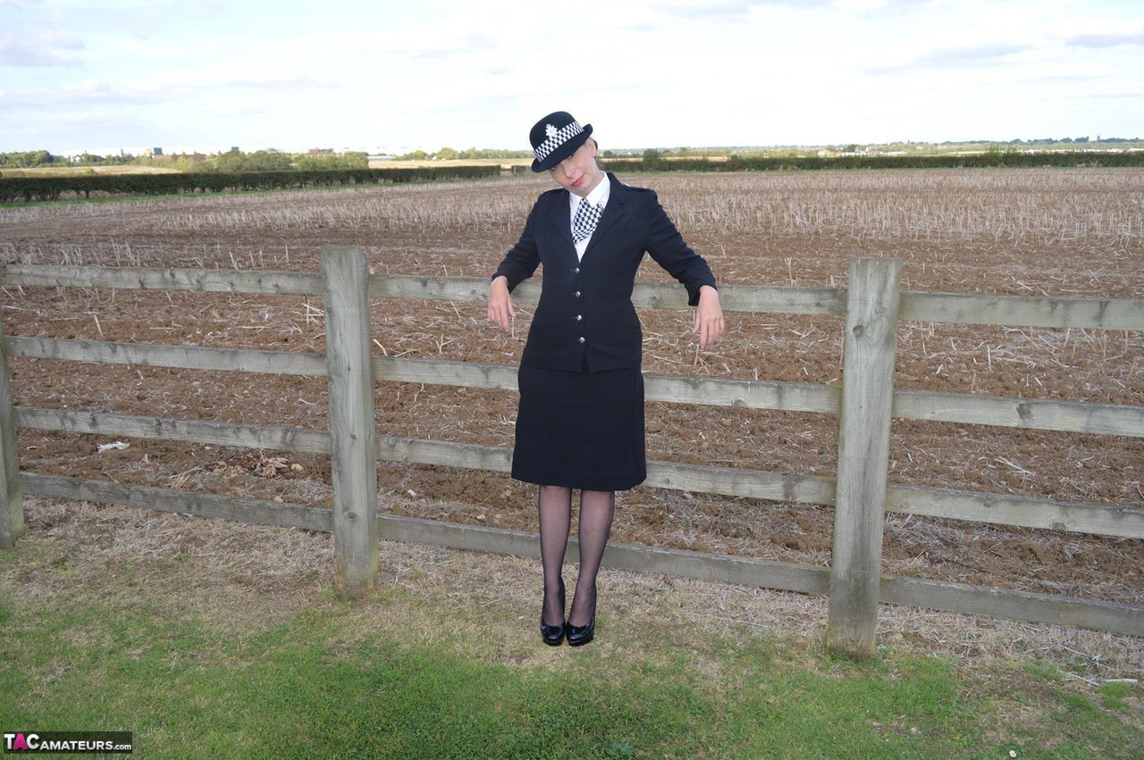 Mature policewoman Barby Slut removes her uniform against a fence at a farm