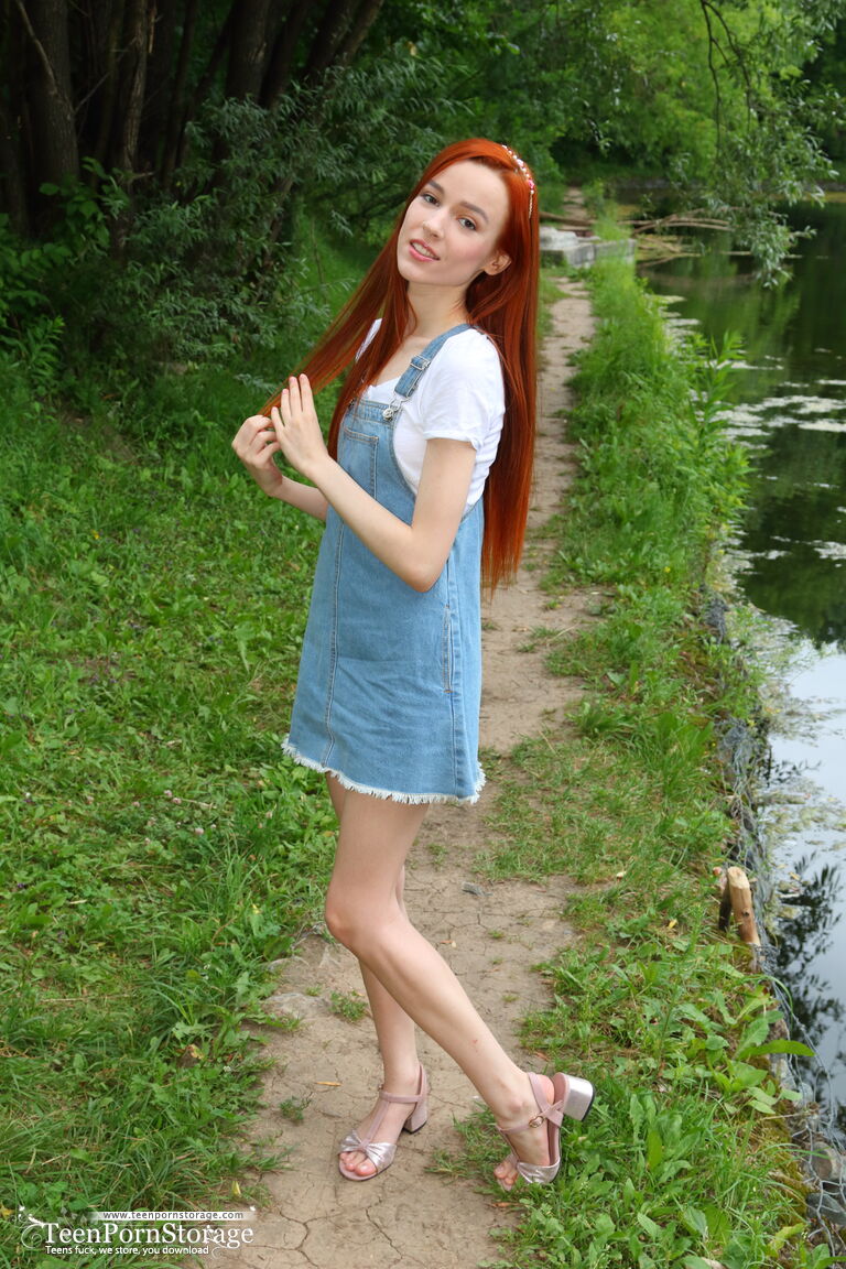 Young redhead Sherice exposes her slender body near a calm body of