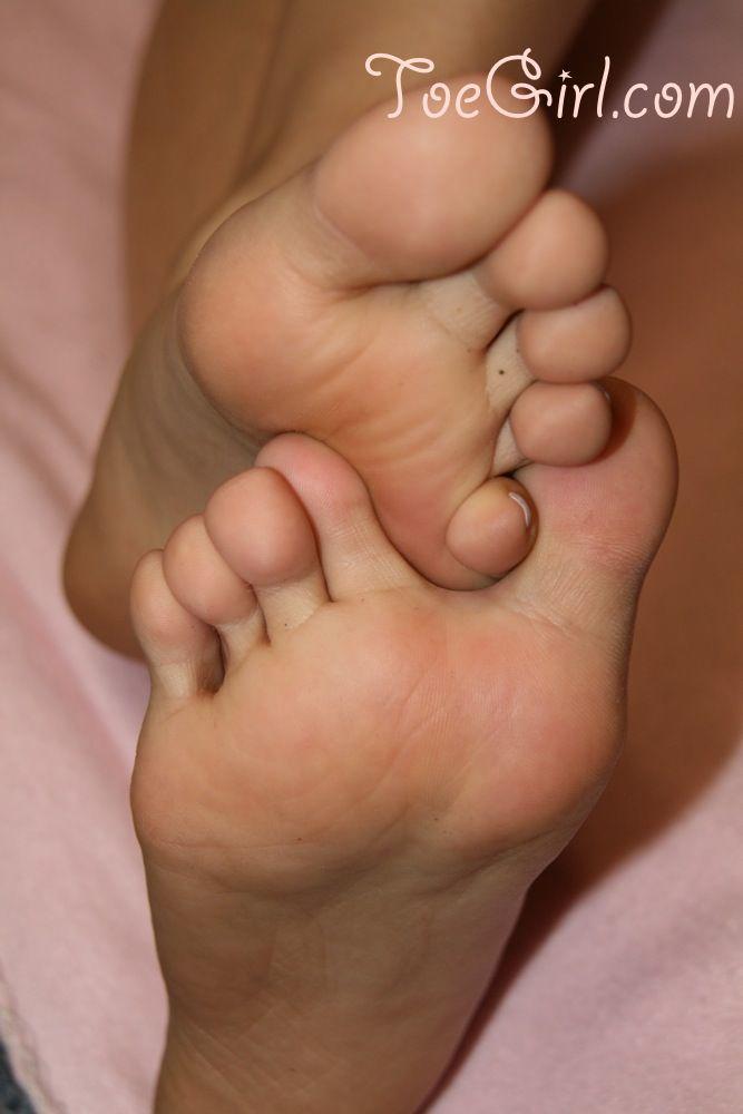 Unknown Caucasian female gently rubs her pretty feet together  